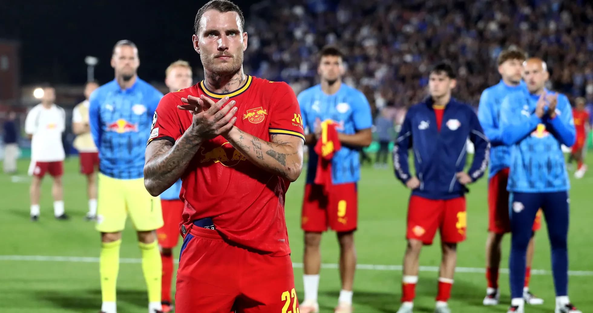 Player in red jersey applauding with teammates behind Player in red jersey applauding with teammates behind