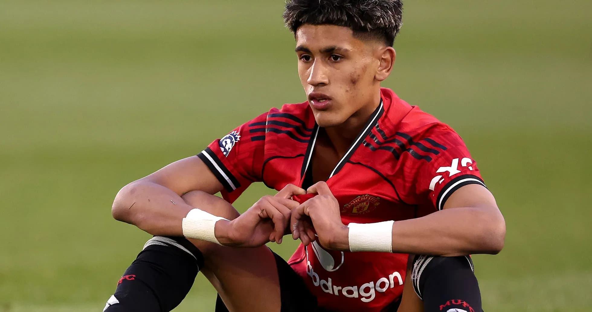 Player sitting on field wearing Manchester United kit Player sitting on field wearing Manchester United kit