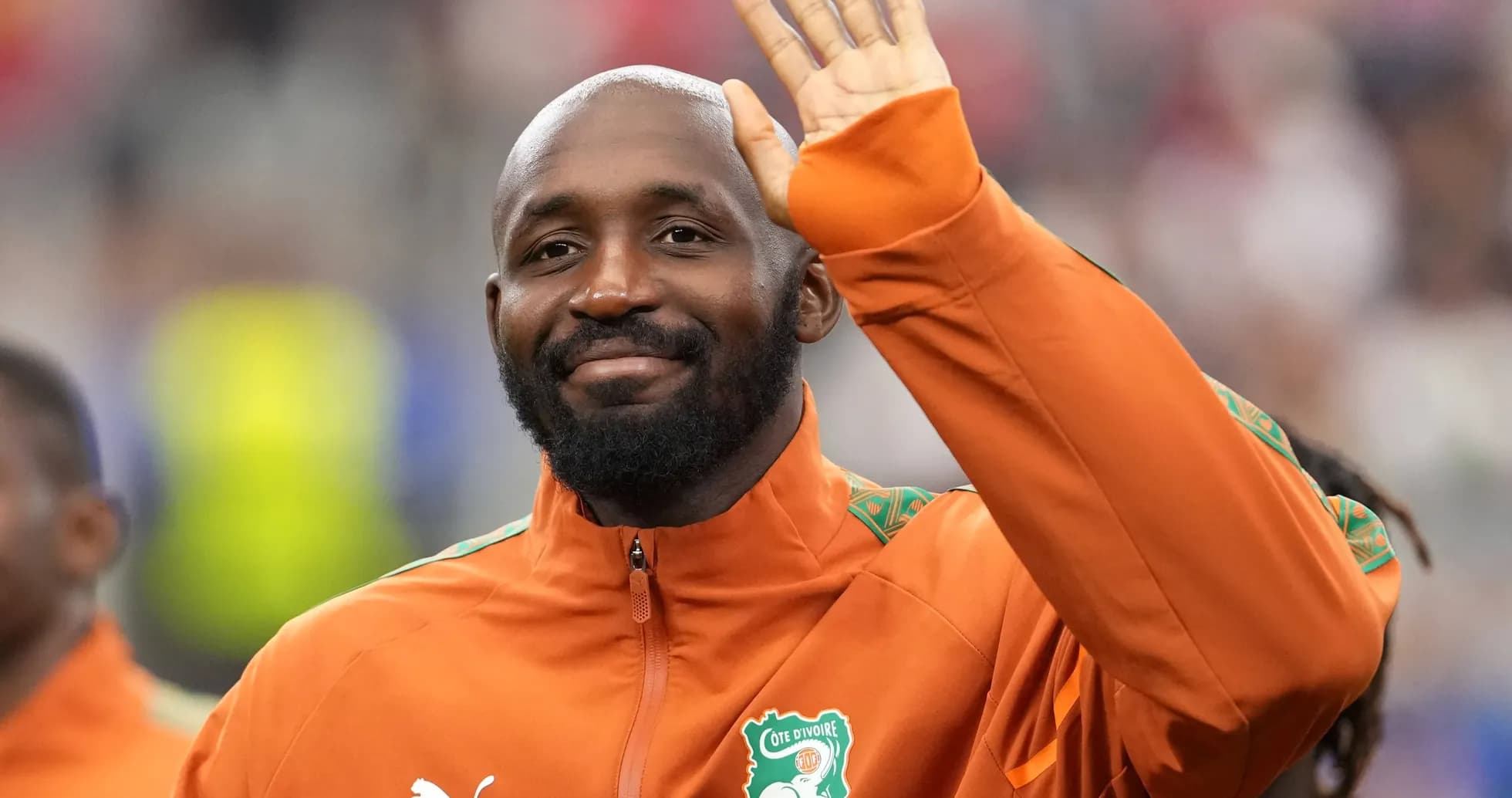 Player waving while wearing Cote d'Ivoire training jacket Player waving while wearing Cote d'Ivoire training jacket