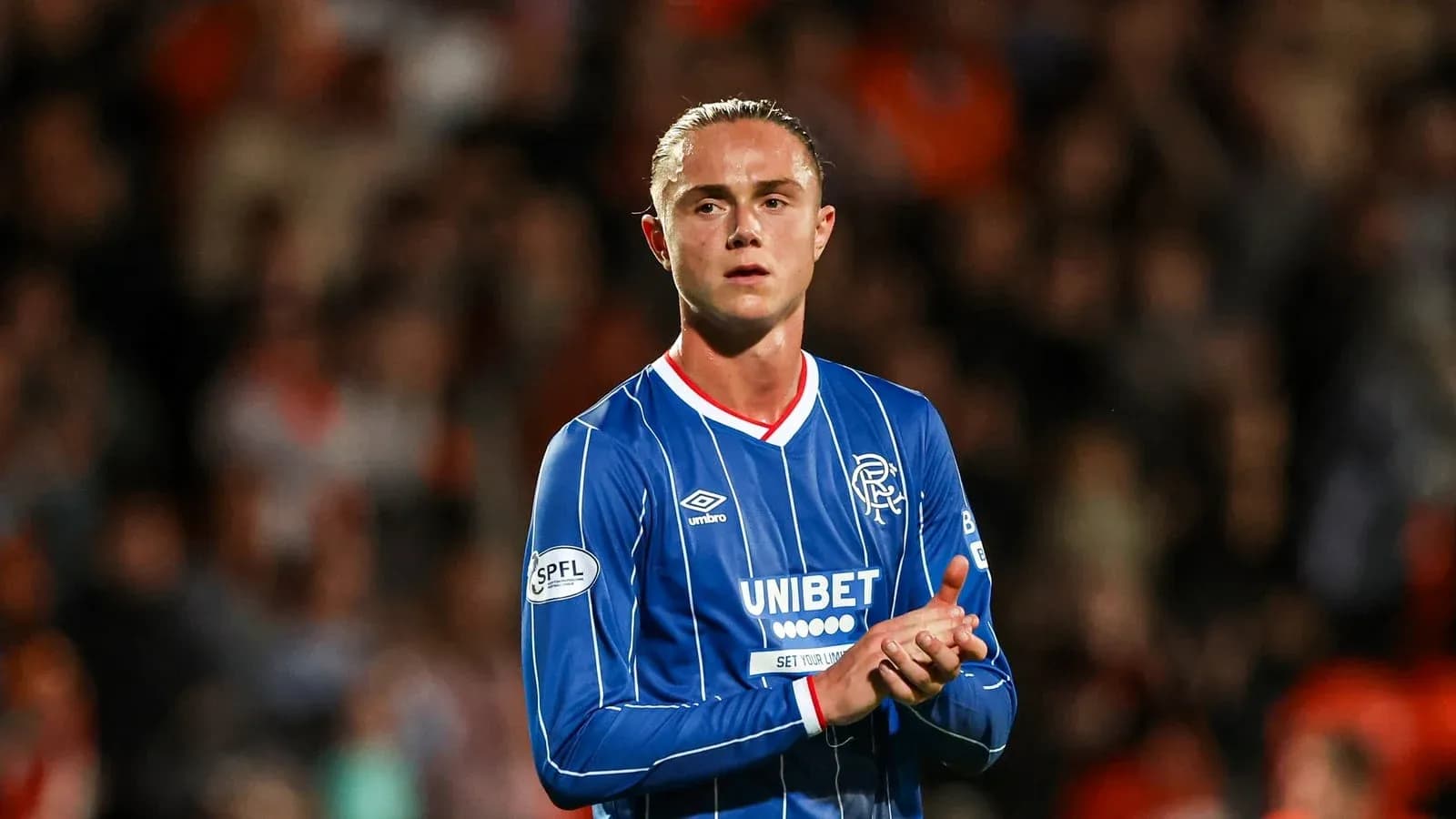 Player in blue jersey applauding fans at stadium Player in blue jersey applauding fans at stadium