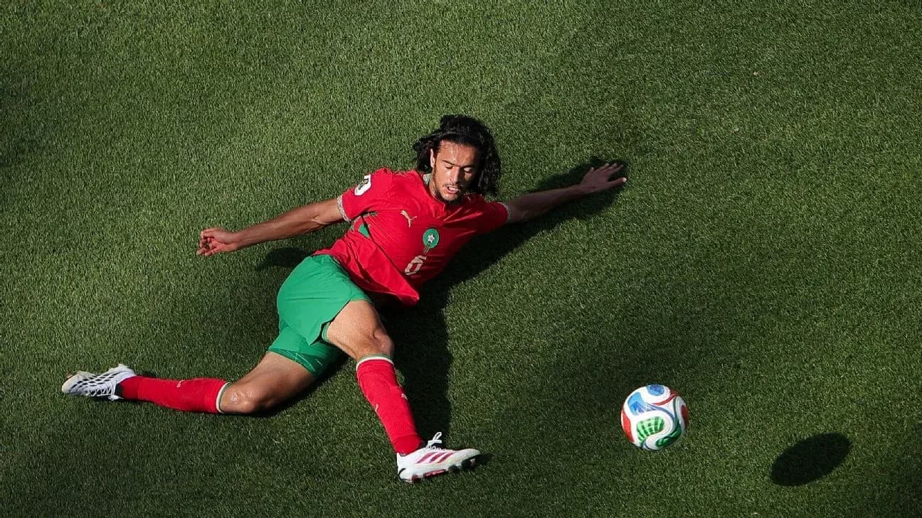 Player in red and green uniform reaching for soccer ball Player in red and green uniform reaching for soccer ball