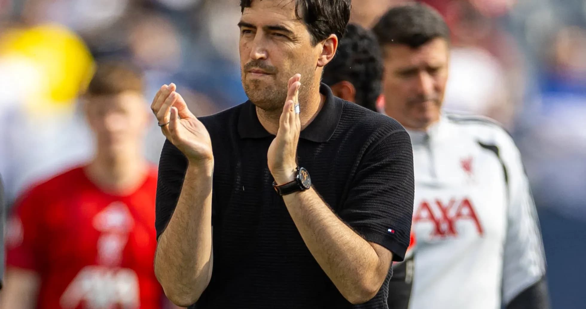 Coach clapping during match with players in background Coach clapping during match with players in background