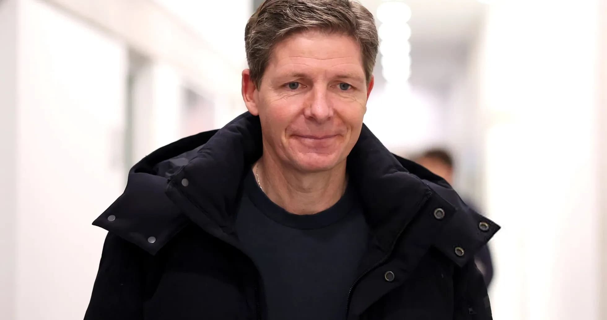 Man walking in a hallway wearing a coat Man walking in a hallway wearing a coat