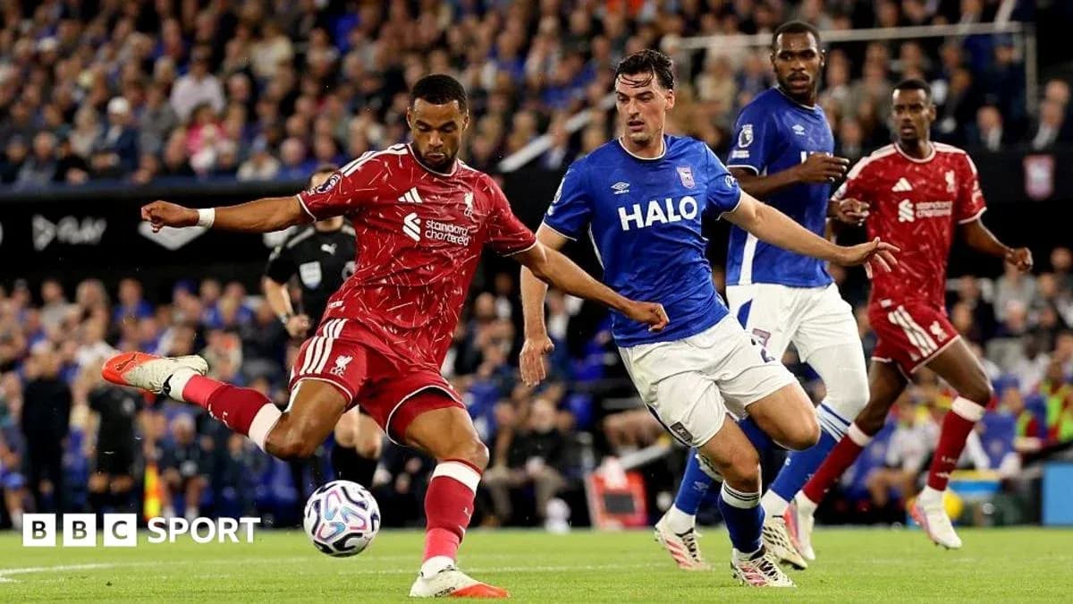 Liverpool player kicking ball past Ipswich defender Liverpool player kicking ball past Ipswich defender