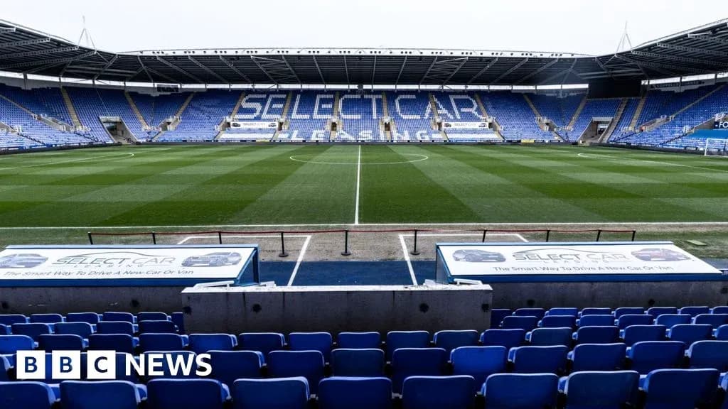 Empty football stadium with blue seating and grass pitch Empty football stadium with blue seating and grass pitch