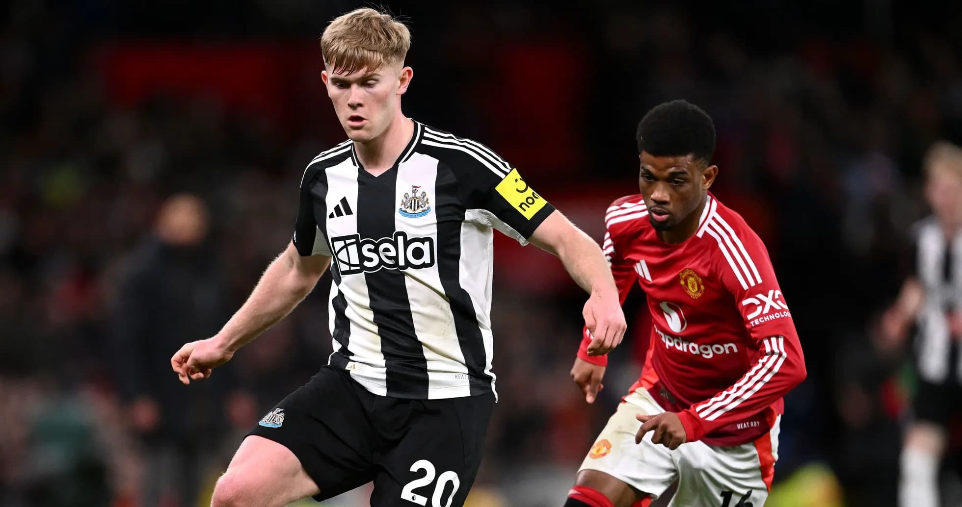 Newcastle player running with ball against Manchester United opponent Newcastle player running with ball against Manchester United opponent