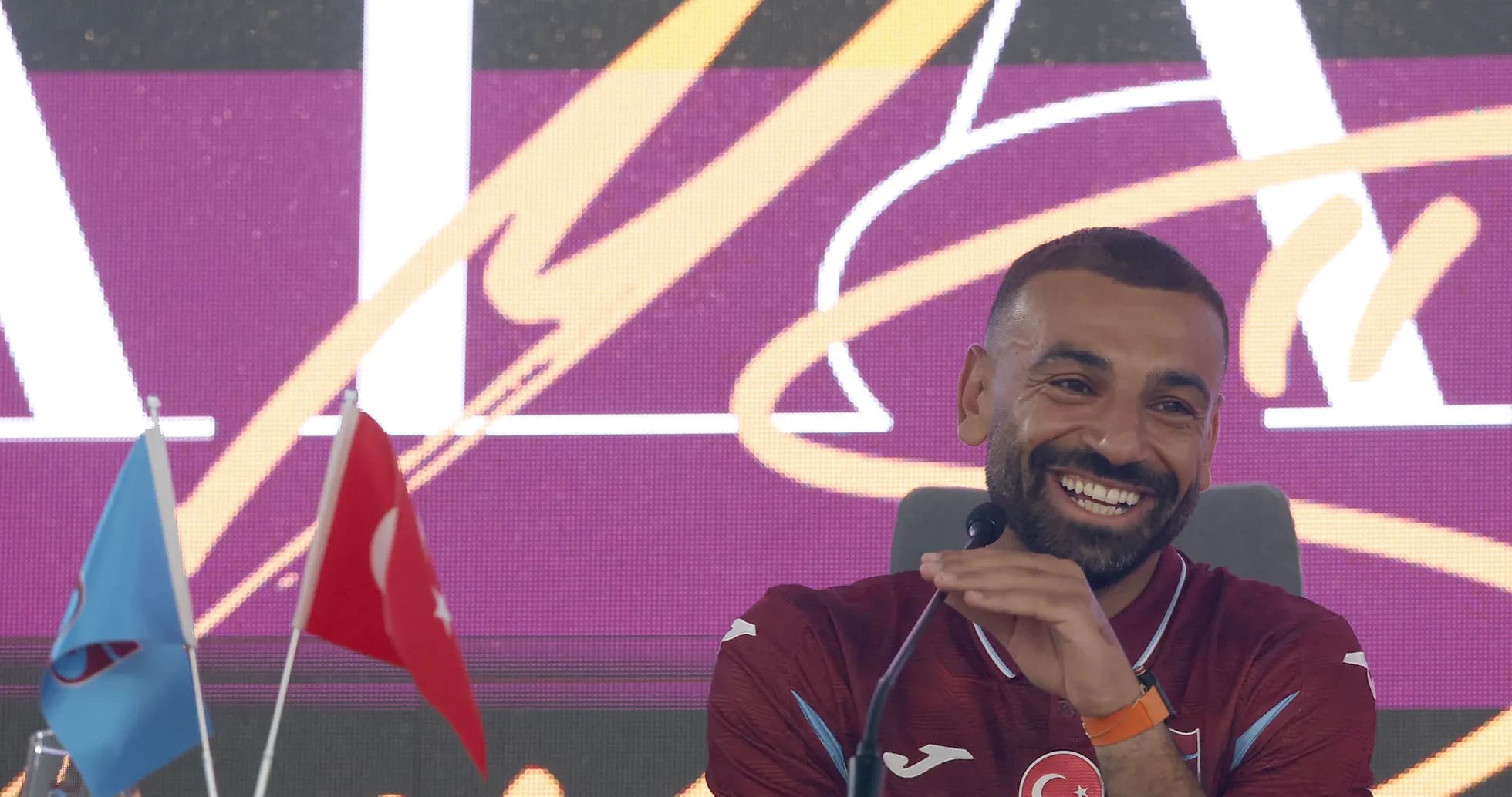 Player speaking at press conference with flags Player speaking at press conference with flags