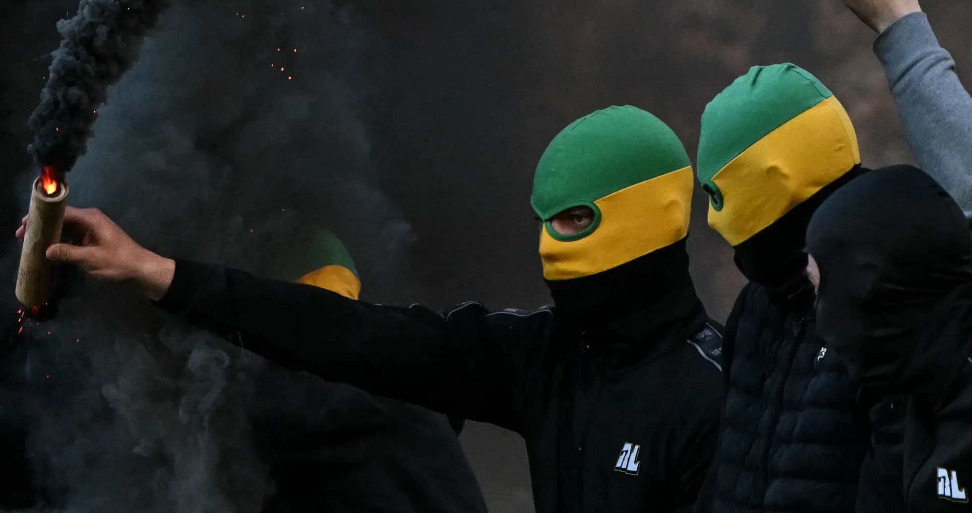 Masked individuals holding flare in smoky environment Masked individuals holding flare in smoky environment