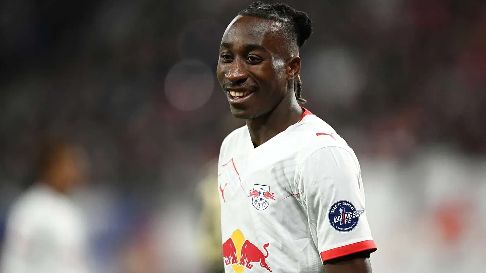 Player smiling in RB Leipzig kit on field Player smiling in RB Leipzig kit on field