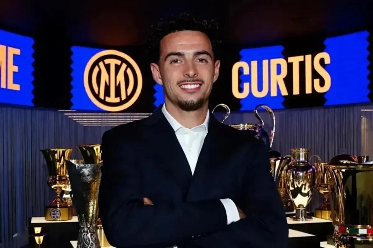 Person posing in front of trophies and club logo Person posing in front of trophies and club logo
