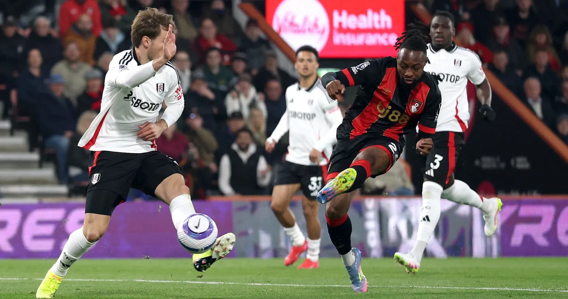 Fulham player challenges Bournemouth player for the ball Fulham player challenges Bournemouth player for the ball