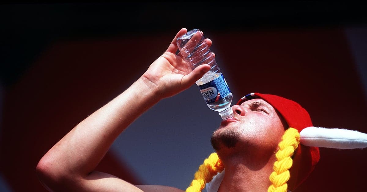 Person drinking water from a bottle in sun Person drinking water from a bottle in sun