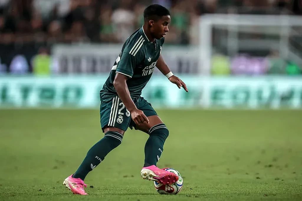 Player in green kit dribbling ball on field Player in green kit dribbling ball on field