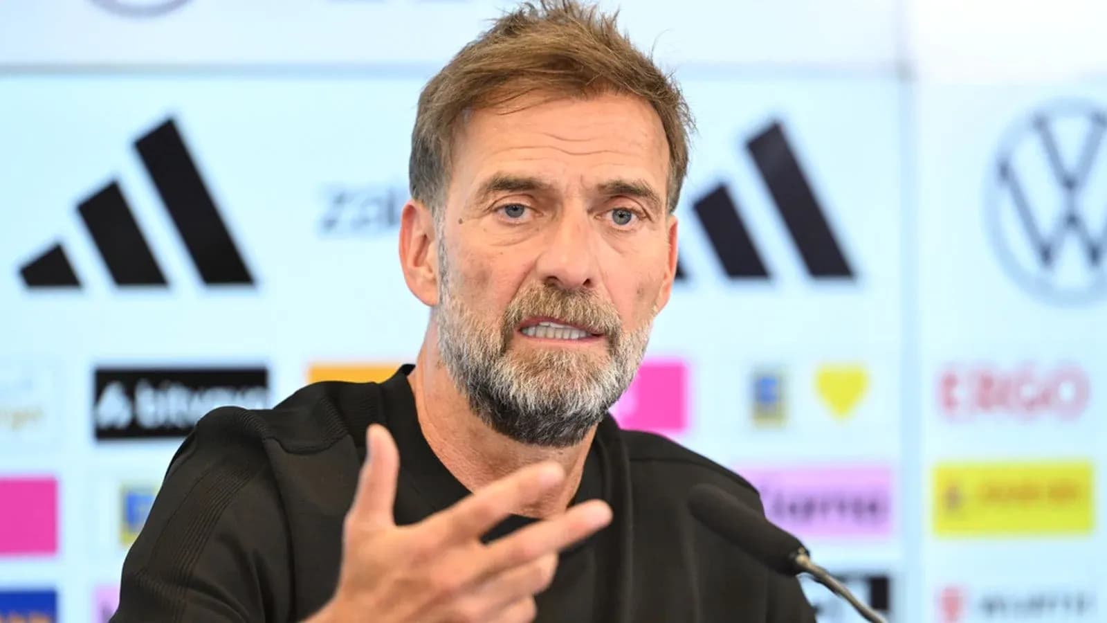 Manager speaking at press conference with logos behind Manager speaking at press conference with logos behind