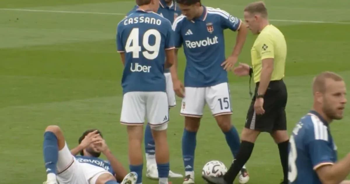 Player on the ground with teammates and referee nearby Player on the ground with teammates and referee nearby