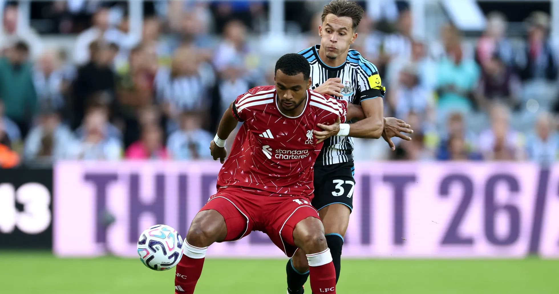 Liverpool player challenged by Newcastle opponent during match Liverpool player challenged by Newcastle opponent during match