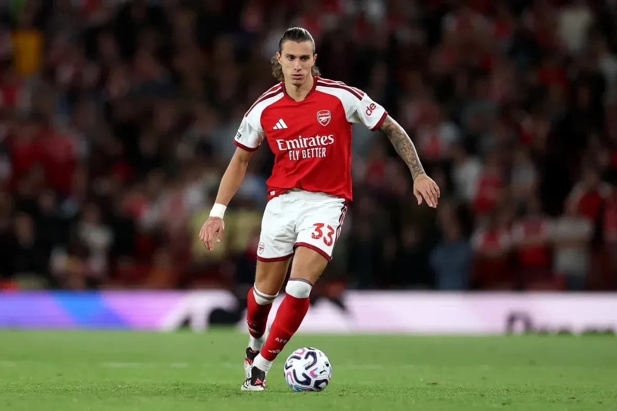 Player in Arsenal kit dribbling ball on pitch Player in Arsenal kit dribbling ball on pitch