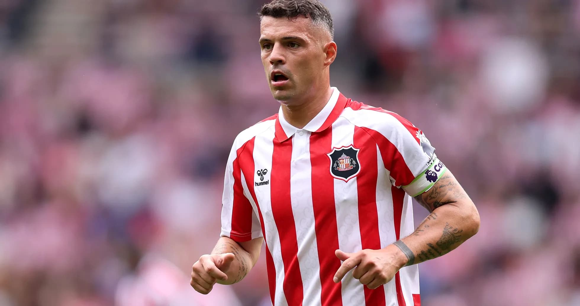 Player in red and white striped jersey on field Player in red and white striped jersey on field