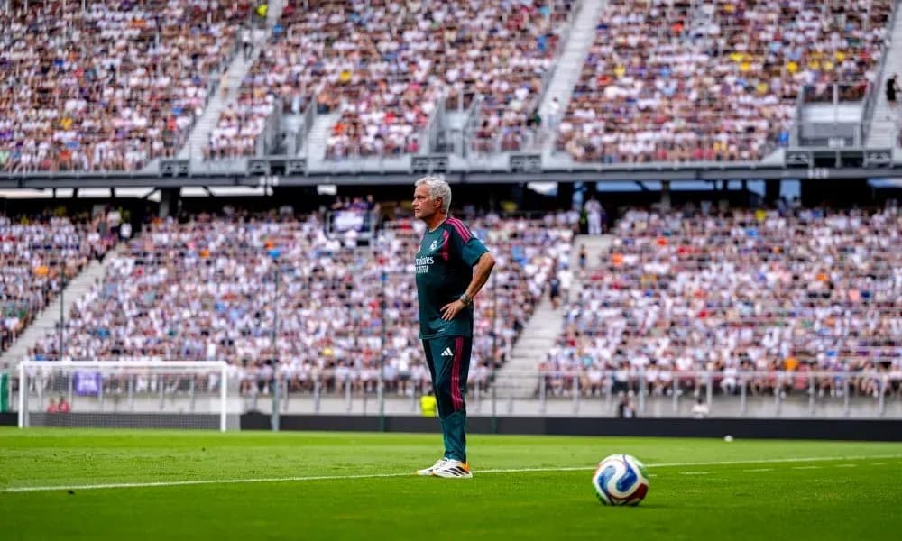 Coach observing match from sideline with crowd in background Coach observing match from sideline with crowd in background