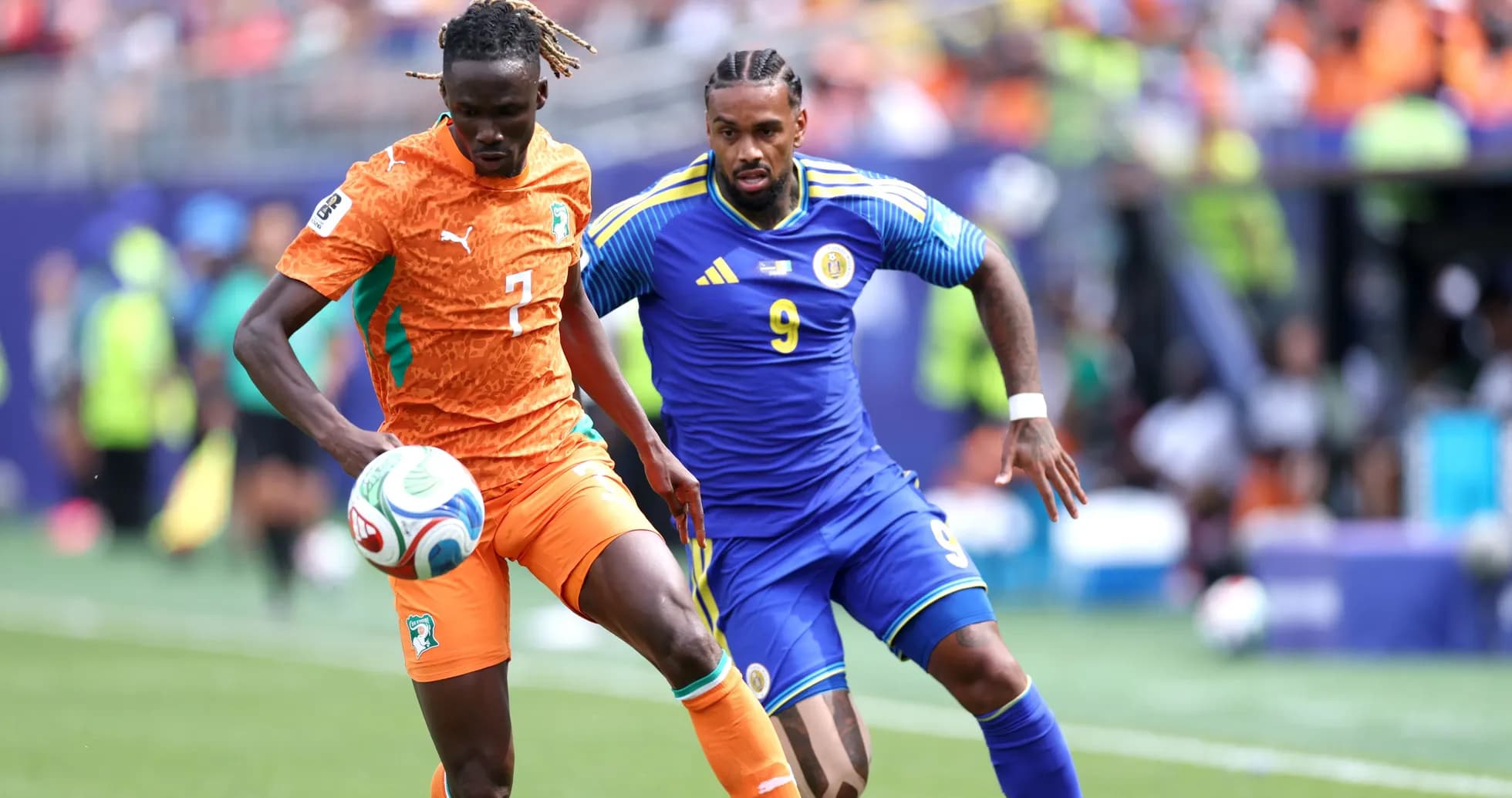 Player in orange dribbling past opponent in blue Player in orange dribbling past opponent in blue