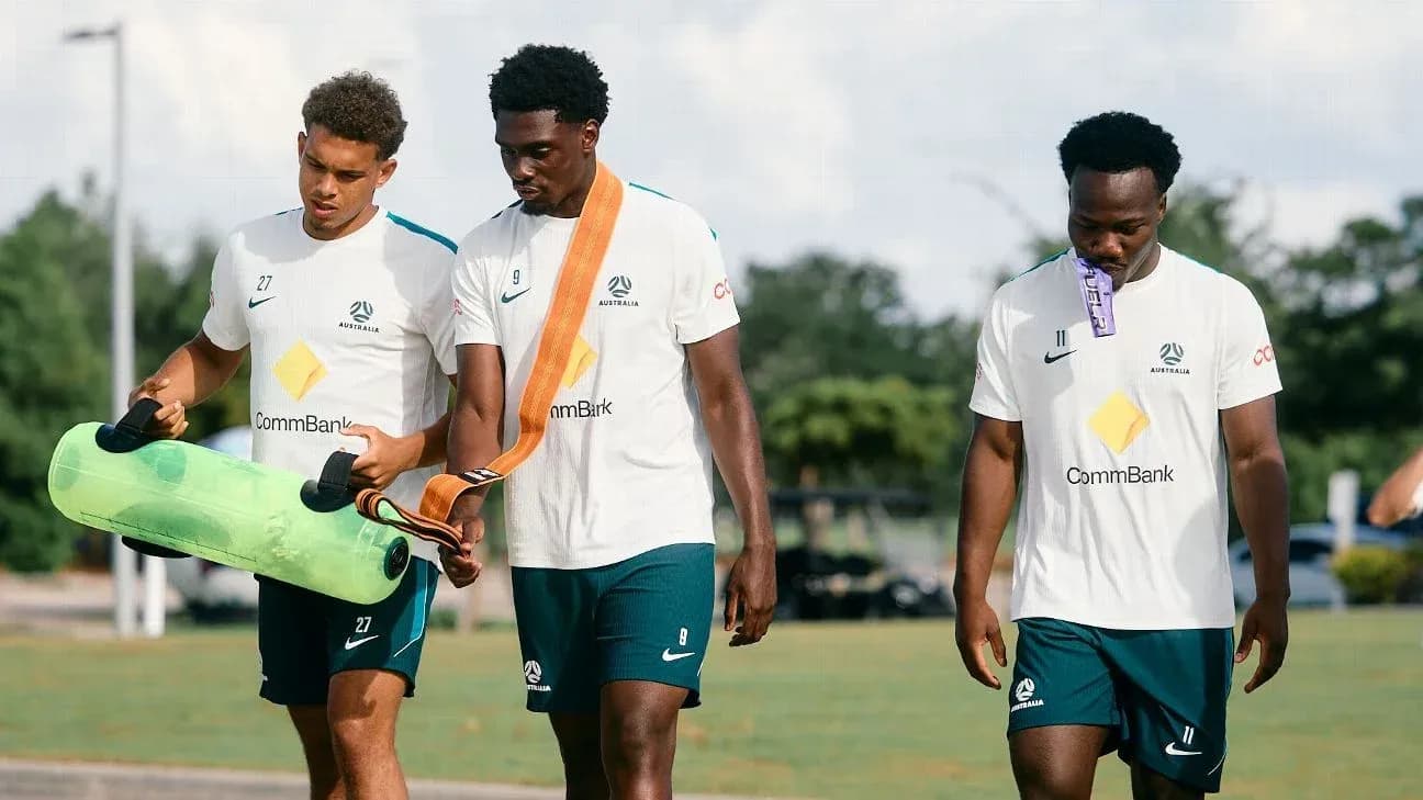 Three Australian players carrying training equipment Three Australian players carrying training equipment