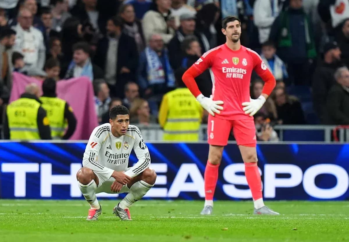 Real Madrid players seated and standing on the pitch Real Madrid players seated and standing on the pitch