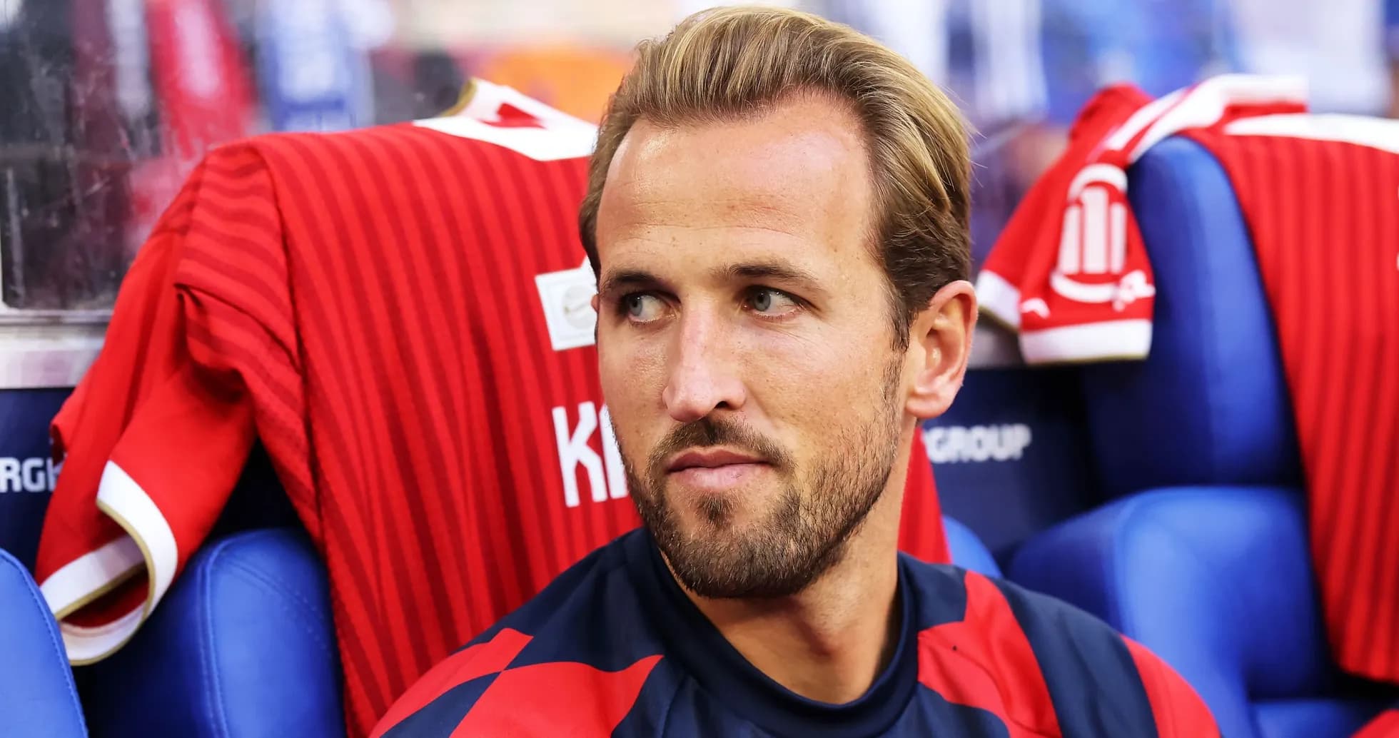 Player seated on bench with red jersey behind Player seated on bench with red jersey behind